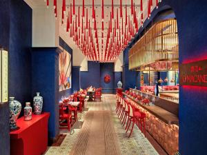 河内Mövenpick Hotel Hanoi Center的餐厅设有红色的桌椅和吊灯