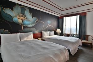 台中市T Hotel的两张床铺,位于酒店房间,墙上挂着鲜花