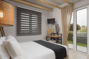 蒂洛斯Tyros Boutique Houses Villas的卧室配有白色的床和窗户。