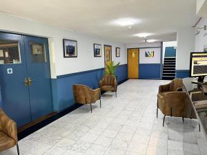 米尔顿凯恩斯MK Hotel的一间设有椅子和蓝色门的等候室