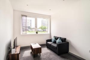 利物浦Modern 1 Bed Apartment in Bootle Liverpool的客厅配有黑色沙发和窗户