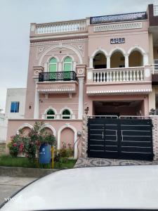 JhelumShah jee guest house的前面有一个黑色门的粉红色房子