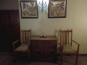香槟谷Inkungu Lodge的一间房间,配有两把椅子、梳妆台、桌子和两张照片