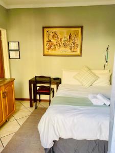 博克斯堡Celtis Lane Guest House的卧室配有一张床和一张桌子,墙上挂着一张照片
