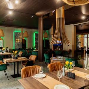 乌日霍罗德Park Hotel Bristol的一间带桌椅和绿灯的餐厅