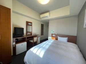 三沢市路由客栈三泽市酒店的一间卧室配有一张床、一张书桌和一台电视。