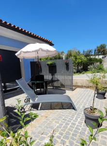 蓬德利马Jardim das Oliveiras - Suítes com Vista的天井配有桌子、遮阳伞和椅子