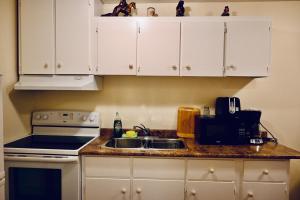 尼亚加拉瀑布Capitol Suite的厨房配有白色橱柜、水槽和炉灶。