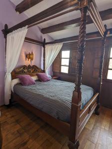 比利亚维西奥萨Las Casas de Isu的一间卧室配有一张带紫色枕头的天蓬床