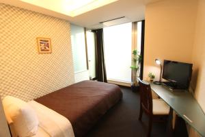 东京HOTEL LiVEMAX BUDGET Korakuen的酒店客房配有一张床和一张书桌及一台电视
