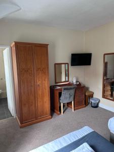 斯卡伯勒East Ayton Lodge Hotel, Scarborough的一间卧室配有书桌、橱柜和电视。
