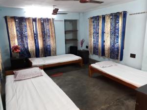 kolkataPushpak Guest House Boys, Near DumDum metro Station的一间设有三张床和窗帘的房间