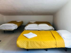 科英布拉NN Guest House的小型客房的两张床,配有黄色毯子