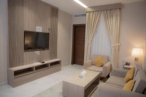 吉达فندق نارس بلس النزهة - Nars Plus Hotel的客厅配有电视、沙发和桌子