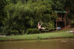 伊塔蒂巴Casa de Vidro com cachoeira的一个人悬在河上的绳子上