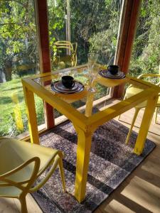 伊塔蒂巴Casa de Vidro com cachoeira的一张黄色桌子,上面有两个盘子和玻璃杯