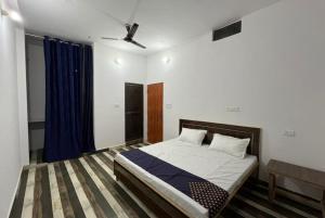 瓦拉纳西Goroomgo Hotel Kashi Nest Varanasi - A Peacefull Stay & Parking Facilities的一间卧室配有床和蓝色窗帘