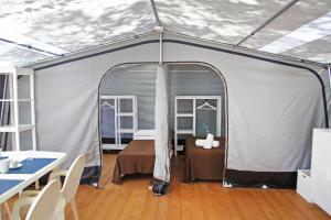 乌真托Riva di Ugento Beach Camping Resort的帐篷配有一张床和一张桌子及椅子
