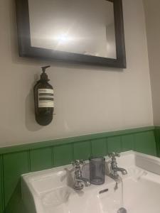 多切斯特The Fox & Hounds Inn的浴室水槽和镜子上的肥皂分配器