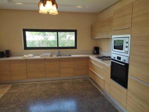 索维拉Villa Golf de Mogador - Piscine - Vue mer 180º的厨房配有木制橱柜和窗户。