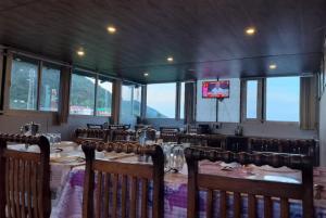 达兰萨拉Hotel Snow Crest Inn - Natural landscape Mountain View的一间带桌椅和电视的用餐室