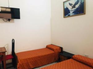布宜诺斯艾利斯Hotel Piamonte的客房设有2张橙色的床和电视。