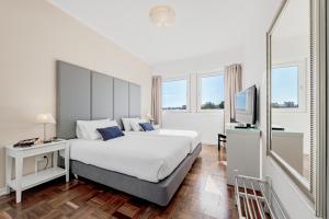 里斯本Lisboa Central Park Hotel Suites & Studios的一间卧室配有一张大床和电视