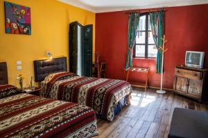 奥塔瓦洛Hostal Riviera Sucre的红色和黄色墙壁的客房内的两张床