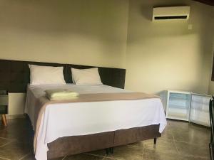 卡皮托利乌Pousada e Camping Recanto da Praia的一间卧室配有一张带白色床单的大床