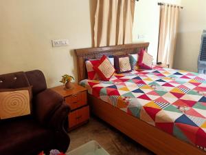 克久拉霍Khajuraho Rancho的一间卧室配有一张带五颜六色被子和椅子的床