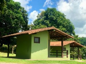 卡皮托利乌Pousada e Camping Recanto da Praia的一座绿色的小建筑,设有瓷砖屋顶
