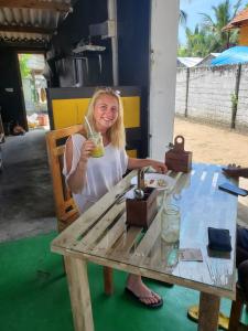 阿鲁甘湾Surf And Stay Arugam Bay的坐在桌子上喝一杯的女人