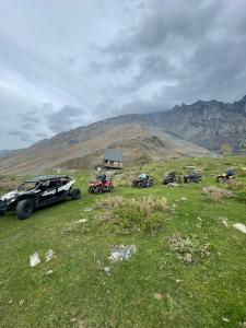 卡兹贝吉mood villa Kazbegi的停在草地山丘上的一群车辆