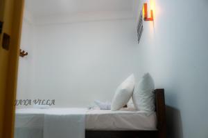 尼甘布Jaya Villa的一张带白色枕头的床和墙上的灯