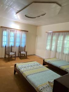 穆里Shangrilla House Murree, Bhurban的客房设有两张床和两把椅子,窗户