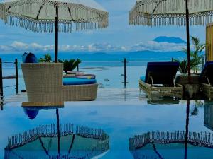 蓝梦岛伦博港和谐酒店的一个带椅子和遮阳伞的游泳池以及大海
