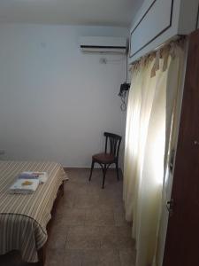 GualeguaychúMilli的配有床、椅子和窗帘的房间