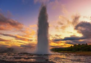 HaukadalurNáttúra Yurtel的水中的一个间歇泉,背景是日落
