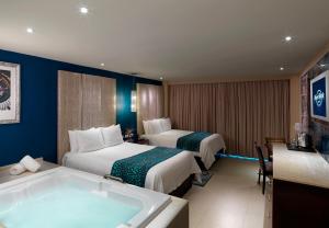坎昆Hard Rock Hotel Cancun - All Inclusive的酒店客房设有两张床和浴缸。