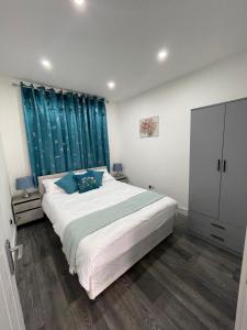 芬奇利Private One Bedroom Flat in Barnet, London的一间卧室配有一张带蓝色窗帘的大床