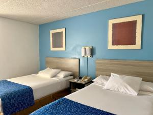 赫尔希赫尔希旅程住宿酒店的两张位于酒店客房的床,拥有蓝色的墙壁