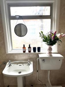 伦敦Charming, Renovated Residence in Willesden Green的一间带水槽的浴室和鲜花窗户