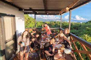 本部Mambo Hostel Okinawa的一群人坐在阳台上的桌子上