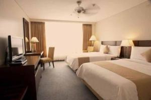 碧瑶A paradise nestled in the City of Pines, Camp John Hay Baguio City的酒店客房设有两张床和电视。