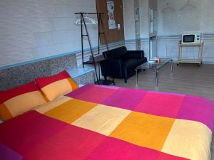 大村市BFH村庄旅馆的一间卧室配有一张色彩缤纷的床和一间客厅。