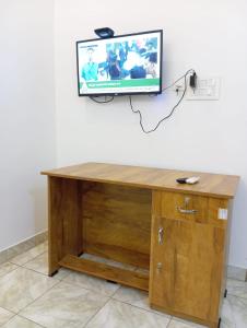 马拉普兰Thekkumpuram Tourist Home的一张木桌,墙上配有电视