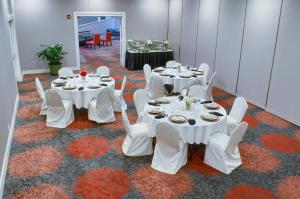 莫比尔提尔曼斯角莫比尔10号州际公路假日酒店的一间设有白色桌子、白色椅子和桌子的房间