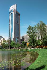成都成都天府丽都喜来登饭店的一座高大的建筑,在城市前方有一个池塘