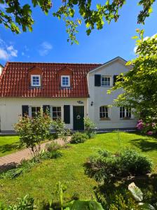 施特拉尔松德Haus mit 110qm und Garten 150m zum Wasser的白色的房子,有红色的屋顶和院子