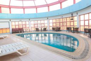 麦纳麦快乐时光酒店的大楼内带桌椅的大型游泳池